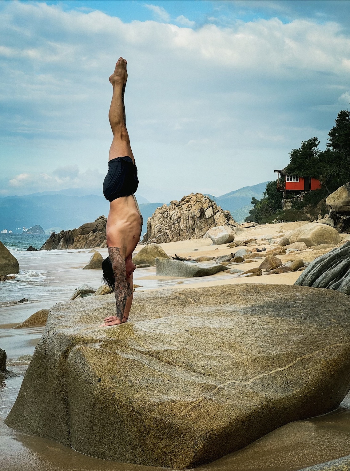 A straight-line handstand held on a rock above the ocean